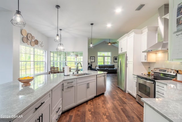 kitchen featuring white cabinets, wall chimney range hood, sink, and appliances with stainless steel finishes