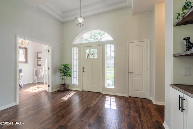 entryway featuring a chandelier, dark wood-style flooring, plenty of natural light, a high ceiling, and baseboards