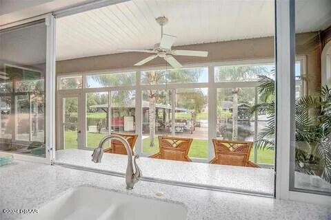 unfurnished sunroom with ceiling fan and sink