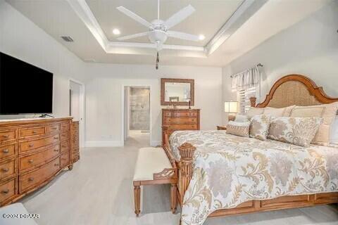 carpeted bedroom featuring ceiling fan and a tray ceiling