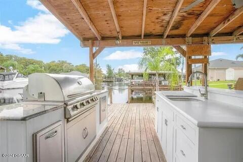 view of patio / terrace featuring exterior kitchen, sink, a grill, and a deck