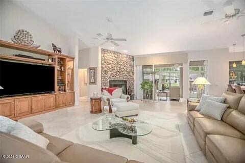 living room with a stone fireplace and ceiling fan