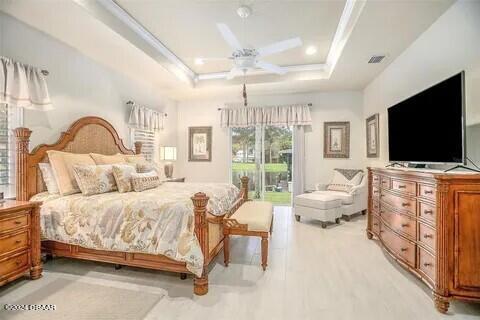 bedroom with access to outside, a tray ceiling, and ceiling fan