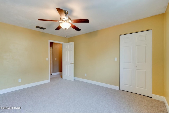 unfurnished bedroom with ceiling fan, a closet, and light carpet