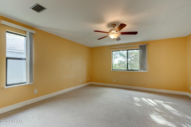 empty room with carpet floors, ceiling fan, and a healthy amount of sunlight