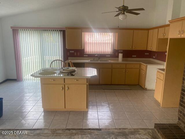 kitchen featuring a sink, a center island, light countertops, lofted ceiling, and ceiling fan