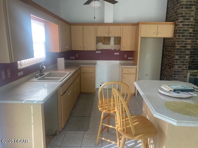 kitchen featuring backsplash, ceiling fan, light countertops, light tile patterned floors, and a sink