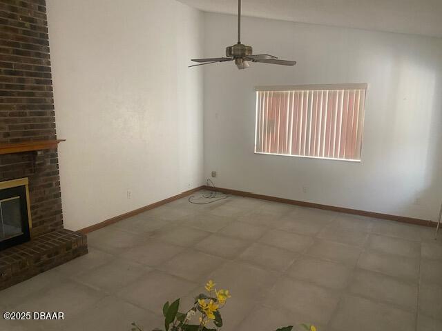 interior space with ceiling fan, a brick fireplace, baseboards, and vaulted ceiling