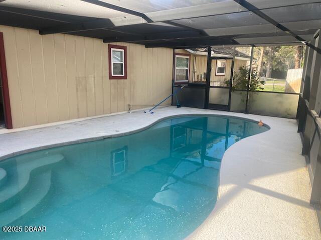 outdoor pool featuring glass enclosure and a patio area