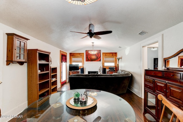 dining area featuring dark wood-type flooring, a textured ceiling, ceiling fan, and vaulted ceiling