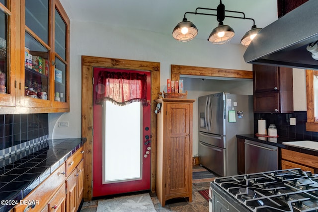 kitchen featuring exhaust hood, pendant lighting, appliances with stainless steel finishes, and tasteful backsplash