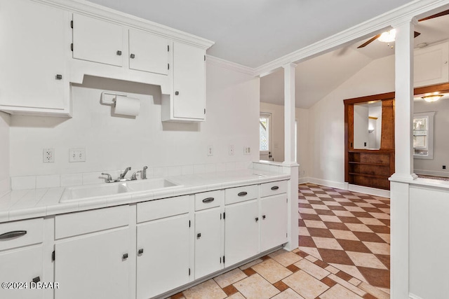 kitchen featuring ornate columns, sink, white cabinets, lofted ceiling, and ceiling fan