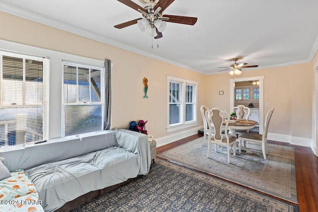 living room featuring dark wood-type flooring, ceiling fan, a healthy amount of sunlight, and crown molding