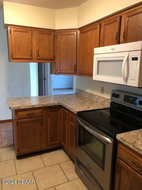 kitchen featuring stainless steel electric stove, a textured ceiling, light tile patterned floors, and kitchen peninsula