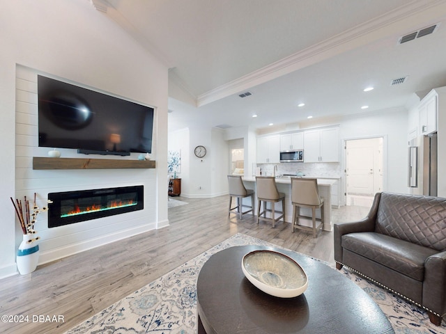 living room featuring crown molding and light hardwood / wood-style floors