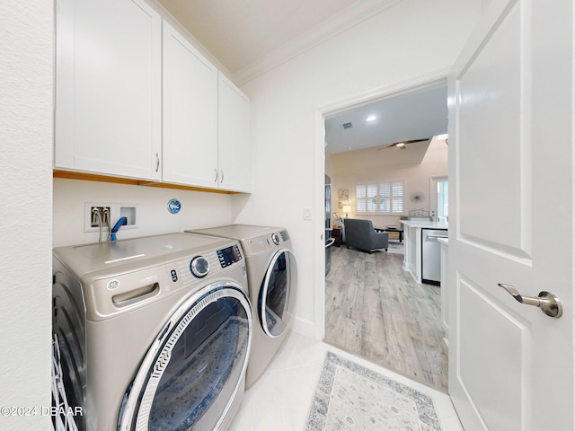 clothes washing area with cabinets, crown molding, light tile patterned floors, and washer and clothes dryer