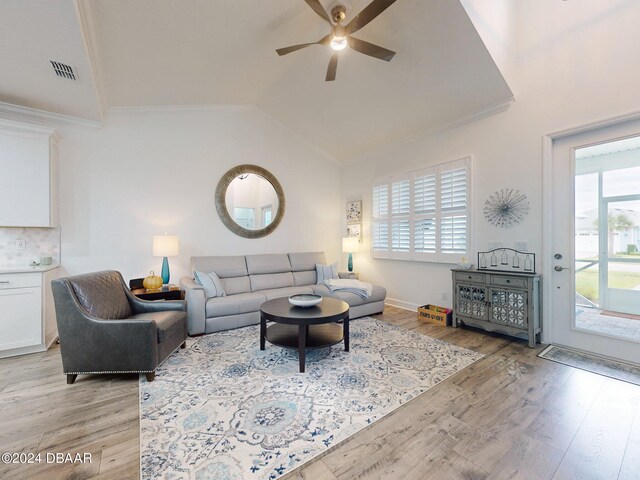 living room with crown molding, ceiling fan, lofted ceiling, and light wood-type flooring