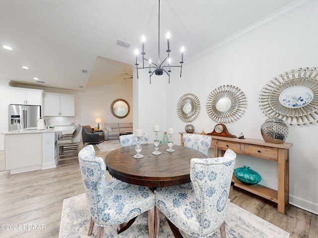 dining area with an inviting chandelier, ornamental molding, and light wood-type flooring