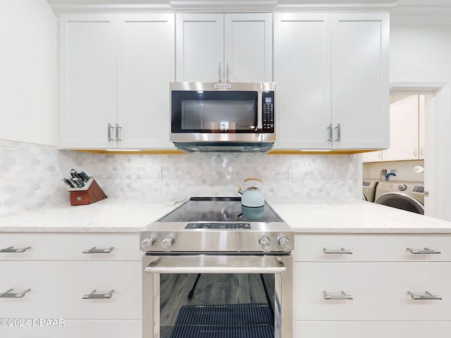 kitchen featuring white cabinetry, stainless steel appliances, tasteful backsplash, light stone countertops, and washer / clothes dryer