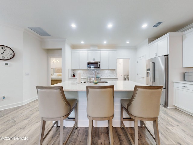 kitchen featuring white cabinetry, stainless steel appliances, and an island with sink