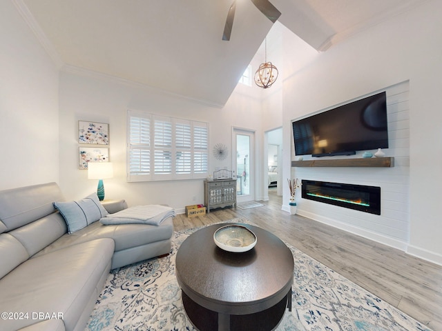 living room featuring an inviting chandelier, hardwood / wood-style floors, crown molding, and a towering ceiling