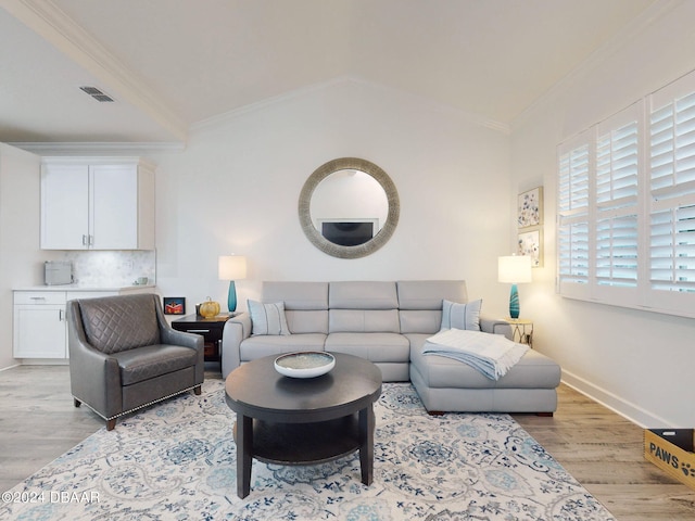 living room featuring crown molding, light hardwood / wood-style flooring, and vaulted ceiling