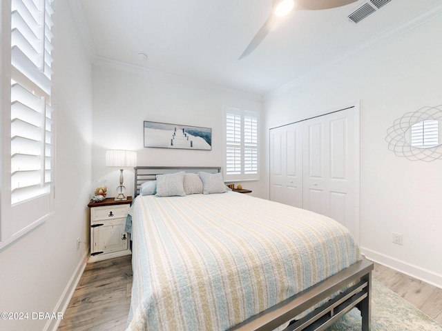 bedroom featuring crown molding, light hardwood / wood-style flooring, a closet, and ceiling fan