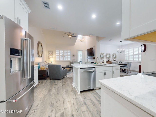 kitchen with sink, white cabinetry, stainless steel appliances, light hardwood / wood-style floors, and ceiling fan with notable chandelier