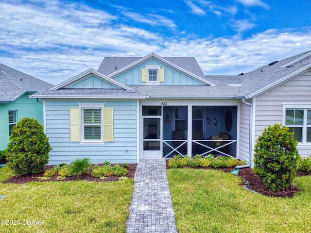 view of front of house featuring a sunroom and a front lawn