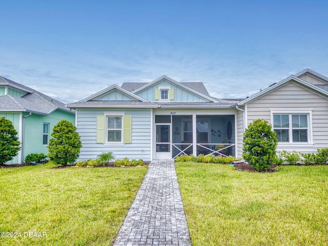 view of front of house featuring a sunroom and a front lawn