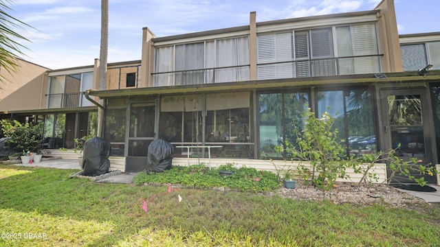 rear view of house with a sunroom and a lawn
