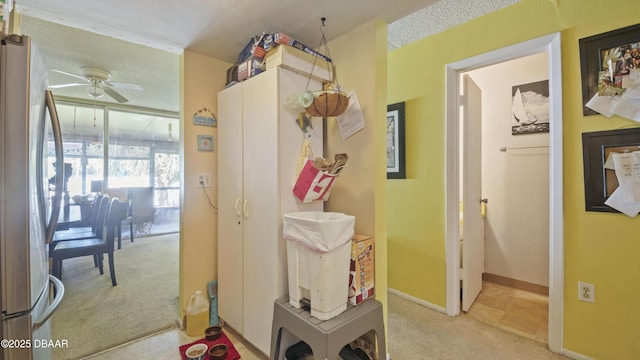 hallway featuring baseboards and light carpet