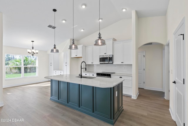 kitchen with stainless steel microwave, a sink, electric range, arched walkways, and white cabinetry