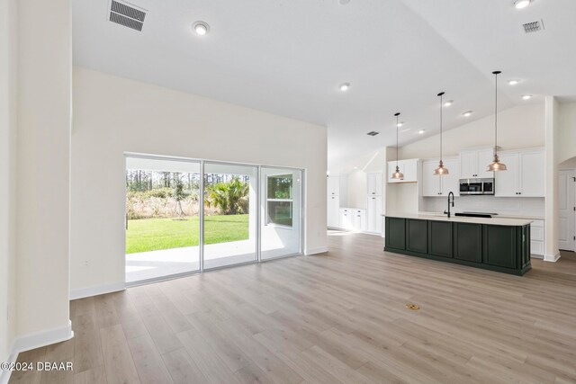 unfurnished living room with a sink, light wood-type flooring, baseboards, high vaulted ceiling, and recessed lighting