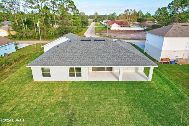 rear view of property with a shingled roof, a yard, and a patio area