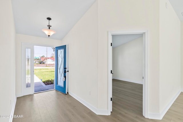 foyer with light wood-type flooring, vaulted ceiling, and baseboards