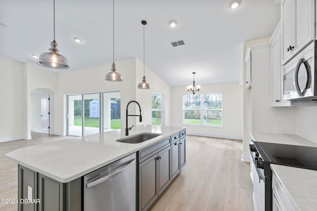 kitchen featuring appliances with stainless steel finishes, a sink, a chandelier, light wood finished floors, and arched walkways