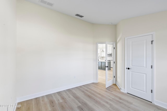 unfurnished bedroom with light wood-style flooring, baseboards, and a sink