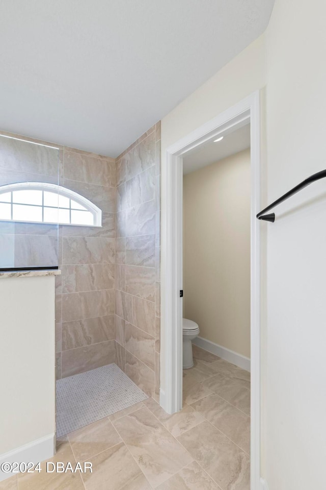 bathroom featuring a walk in shower, toilet, baseboards, and tile patterned floors