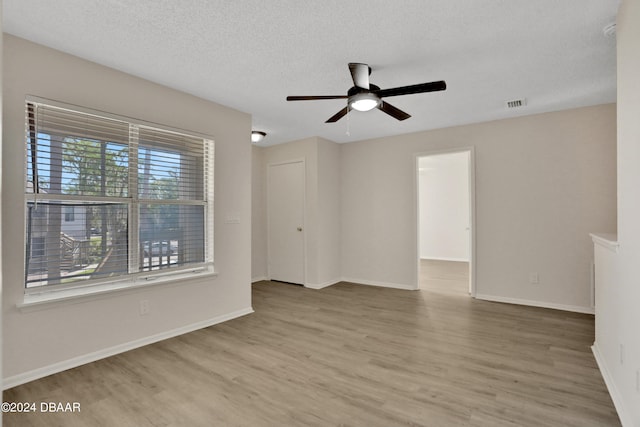 unfurnished room with a wealth of natural light, hardwood / wood-style flooring, and ceiling fan