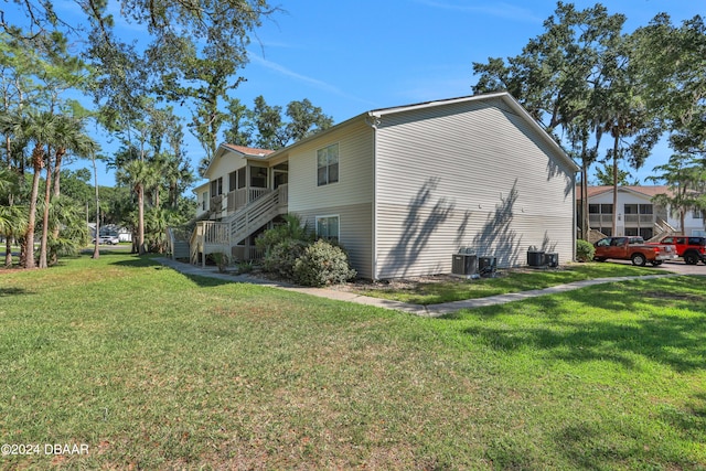 view of side of property featuring central air condition unit and a lawn