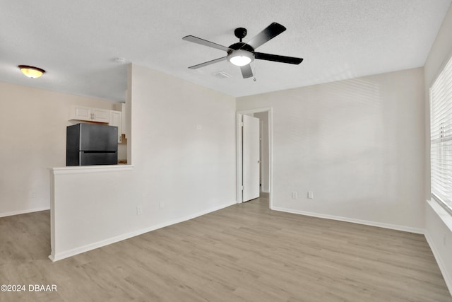 empty room with light wood-type flooring, a textured ceiling, and ceiling fan