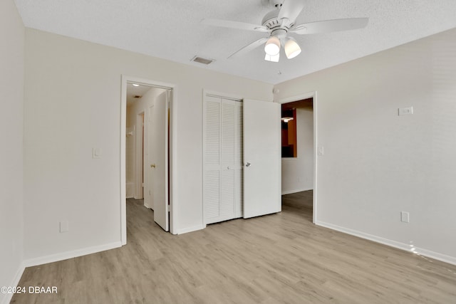 unfurnished bedroom featuring a textured ceiling, light hardwood / wood-style floors, ceiling fan, and a closet