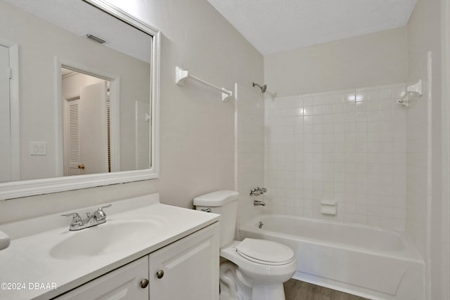 full bathroom featuring hardwood / wood-style flooring, a textured ceiling, vanity, toilet, and tiled shower / bath combo