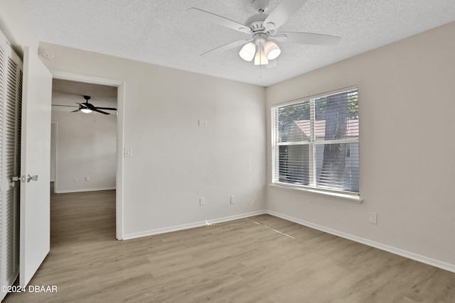 unfurnished bedroom with ceiling fan, a textured ceiling, a closet, and light hardwood / wood-style flooring