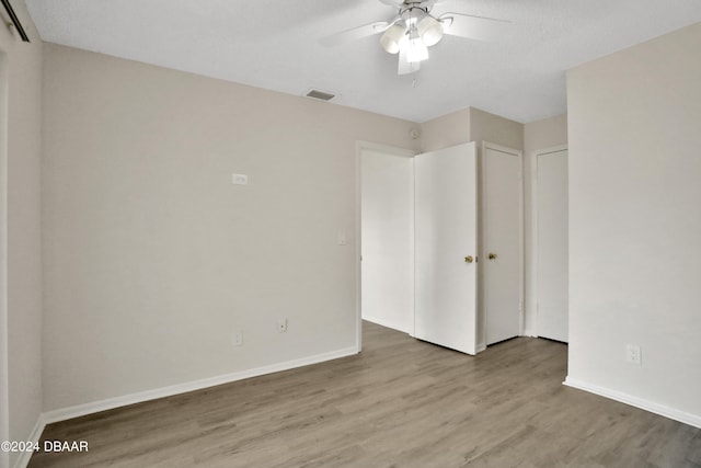 unfurnished bedroom with a textured ceiling, hardwood / wood-style floors, and ceiling fan