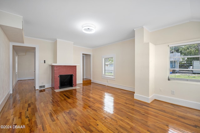 unfurnished living room with hardwood / wood-style floors, ornamental molding, and a fireplace