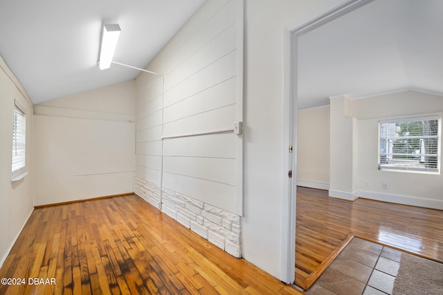 unfurnished room with hardwood / wood-style floors and vaulted ceiling