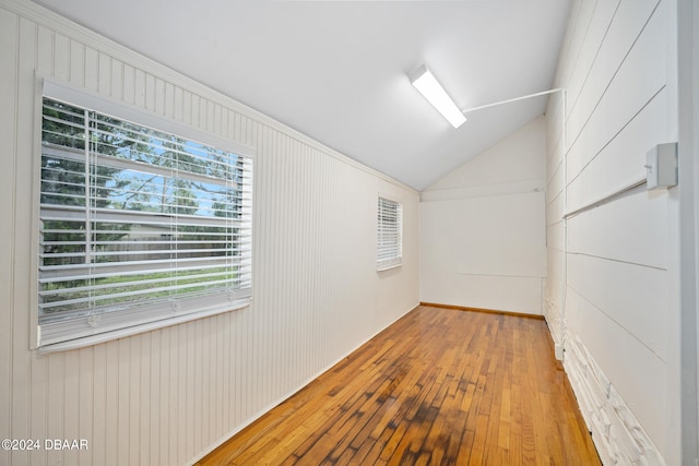 interior space featuring plenty of natural light, wooden walls, light hardwood / wood-style flooring, and lofted ceiling