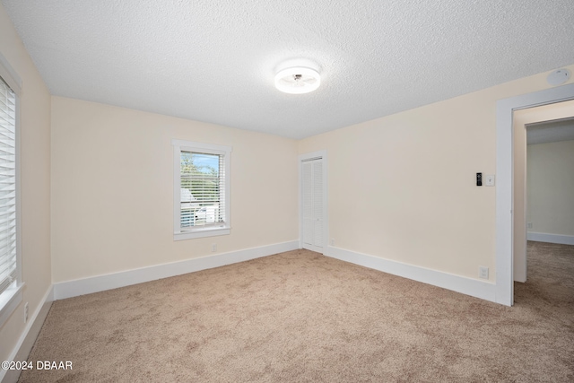 spare room with carpet flooring and a textured ceiling